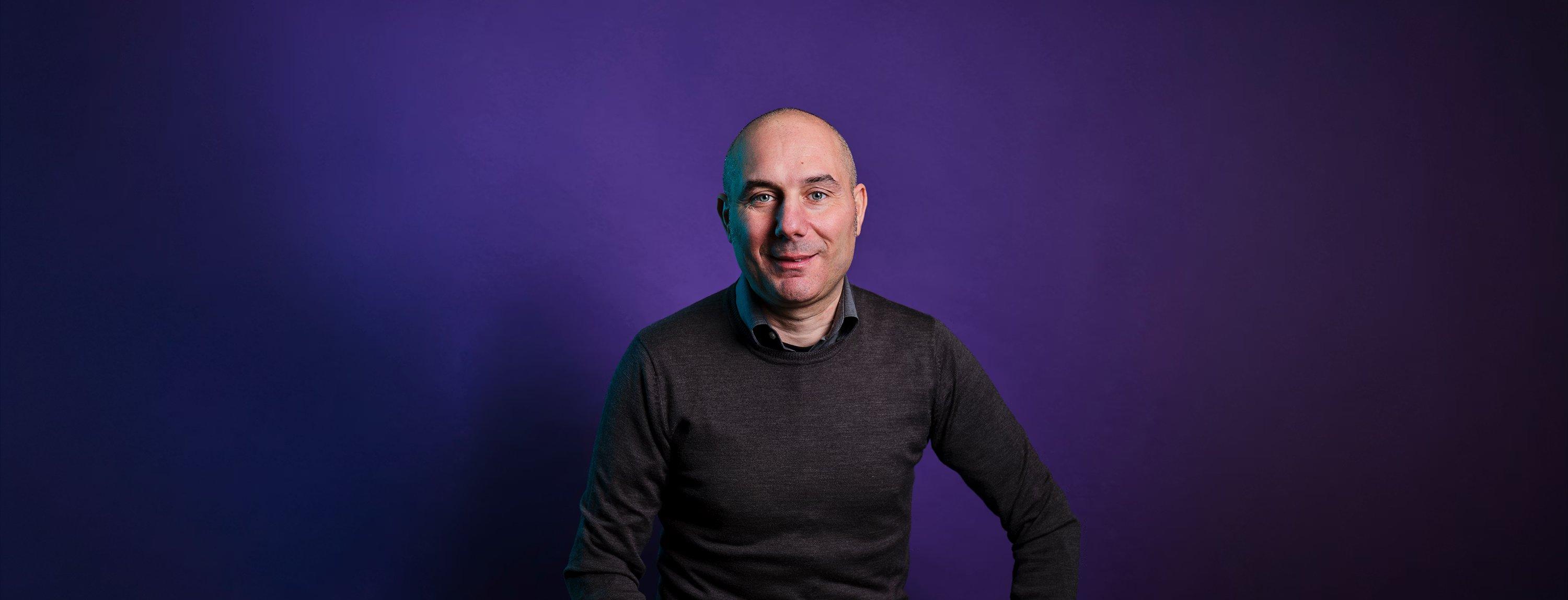 Portrait of Antonio Mazza, Country Head of wamo Italy, seated against a dark purple studio backdrop