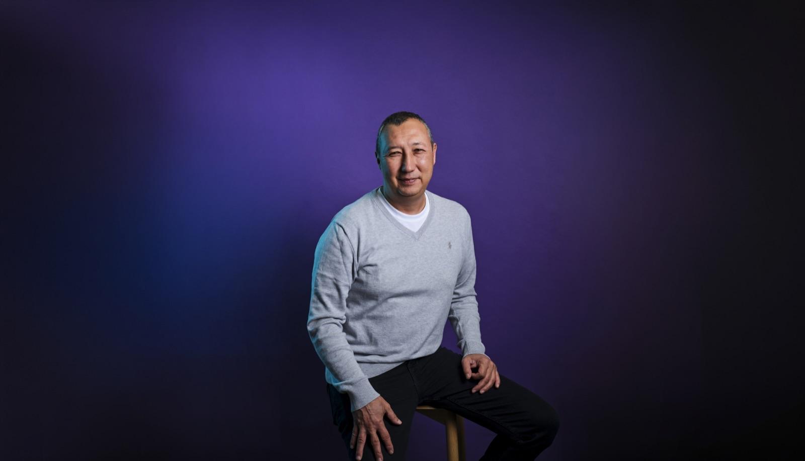 Portrait of Yankı Onen, seated against a purple-to-black gradient background