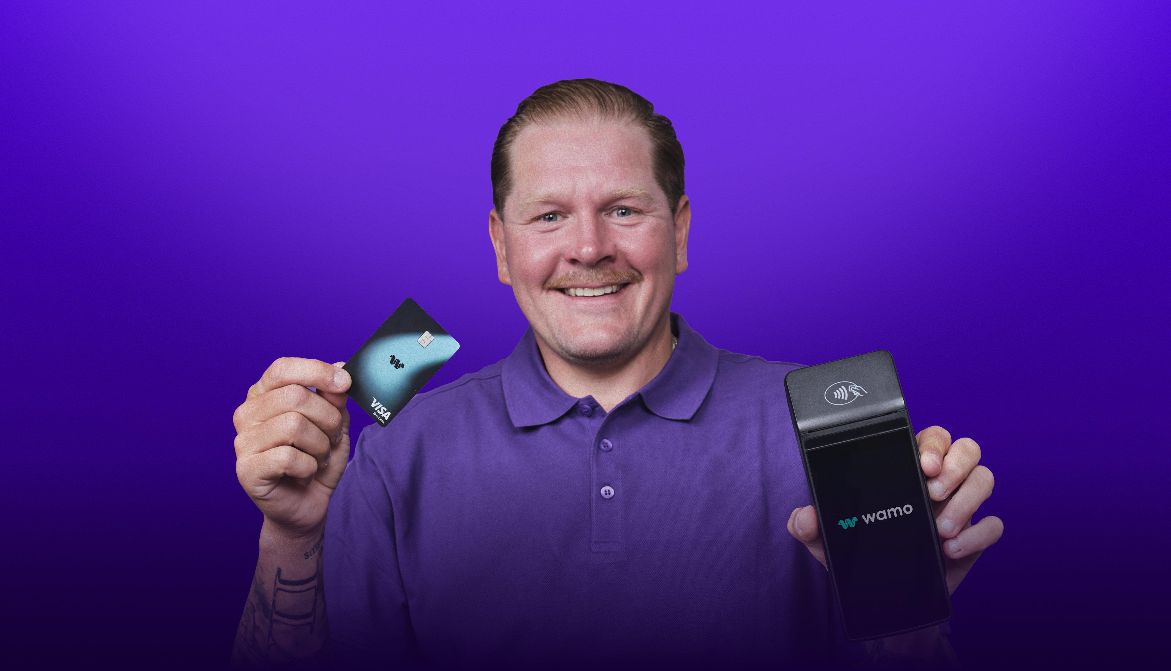 Petri Kontiola smiling and holding a wamo Visa Business card and a wamo card reader against a purple studio backdrop