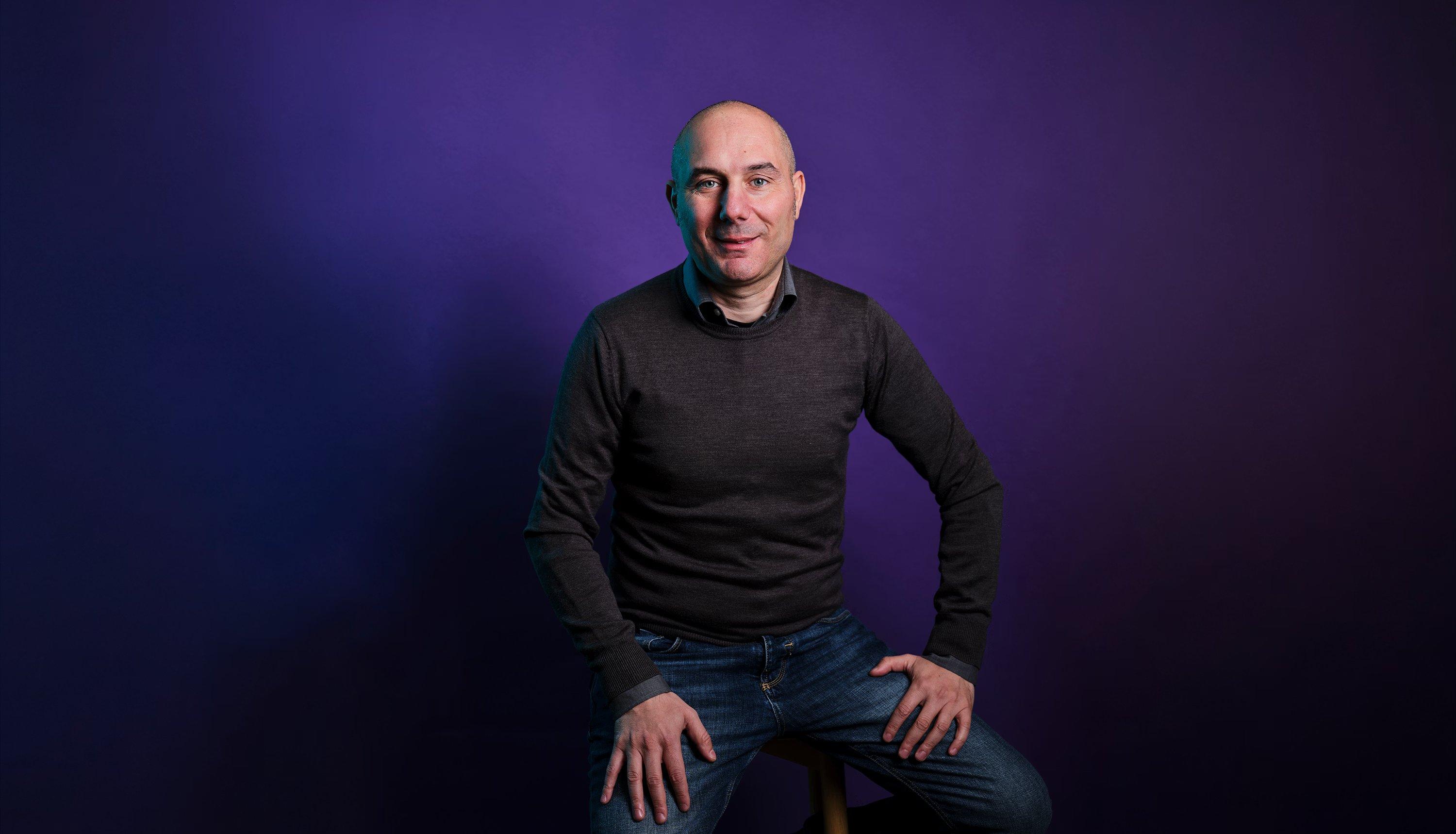 Portrait of Antonio Mazza, Country Head of wamo Italy, seated against a dark purple studio backdrop