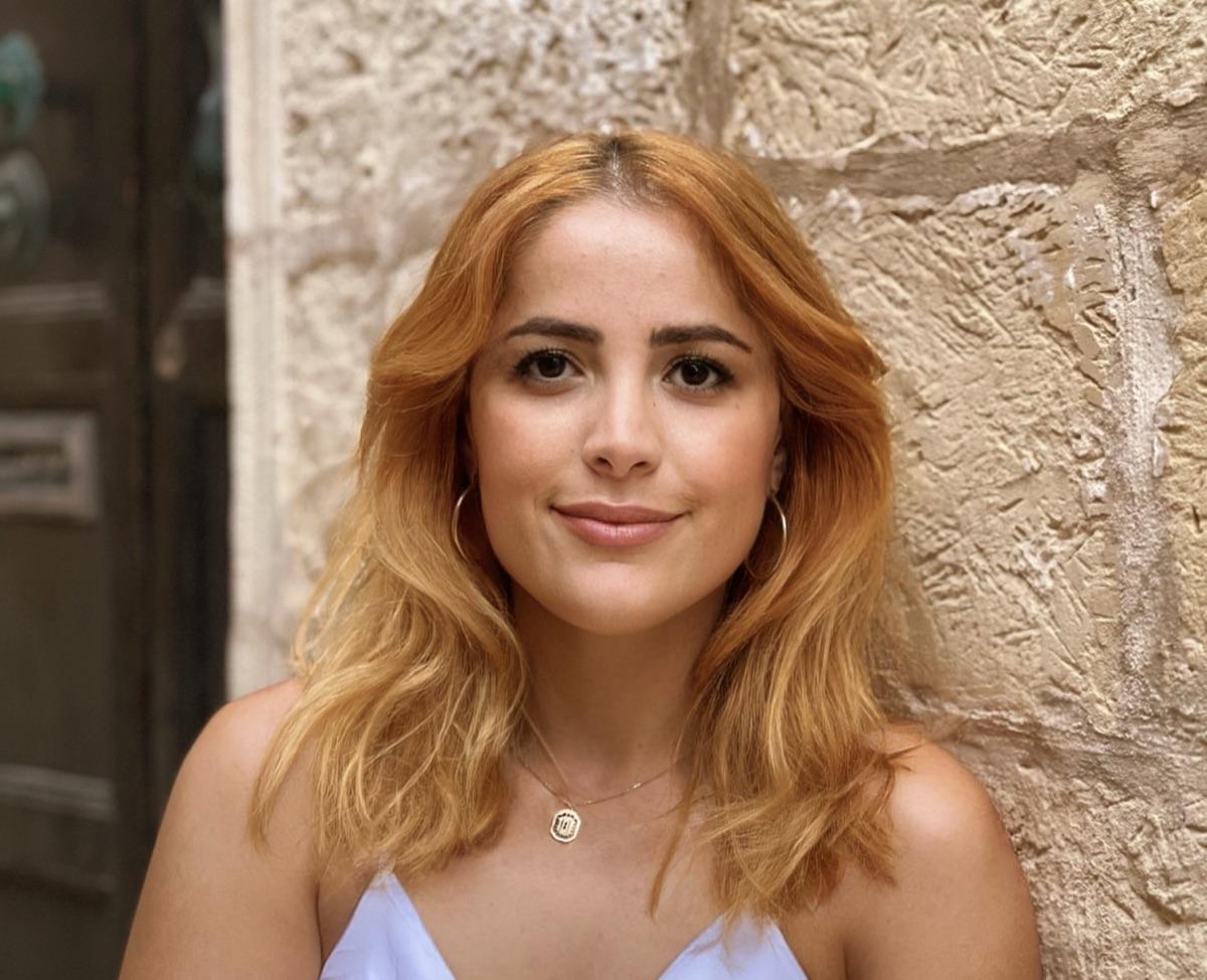 Portrait of Hatice, AML Team Lead in Compliance at wamo, smiling against a stone wall