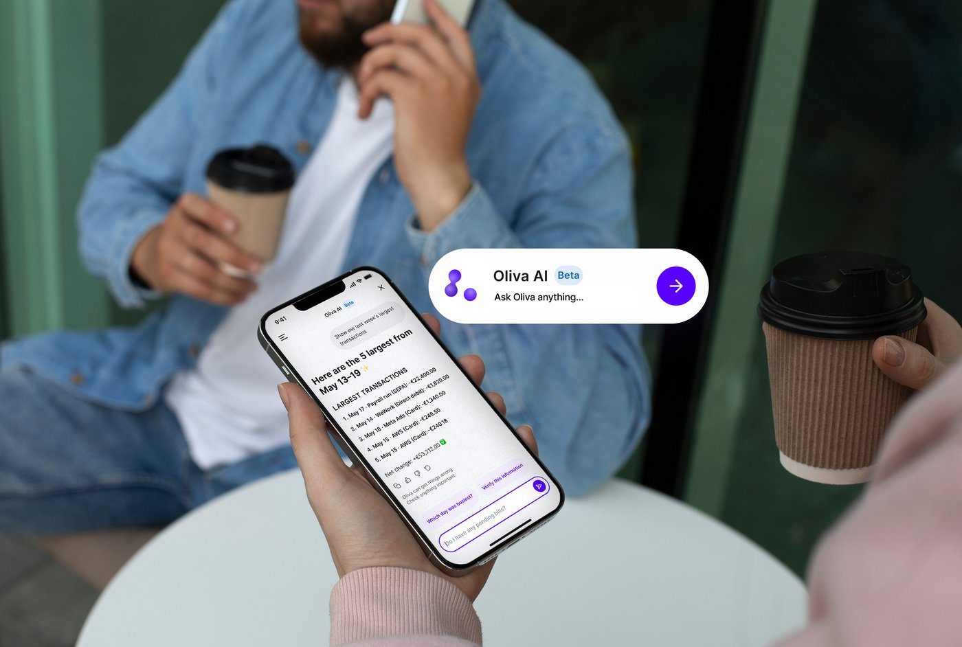 Two people at a cafe table, one holding a phone showing an Oliva AI chat that lists the five largest transactions from May 13-19